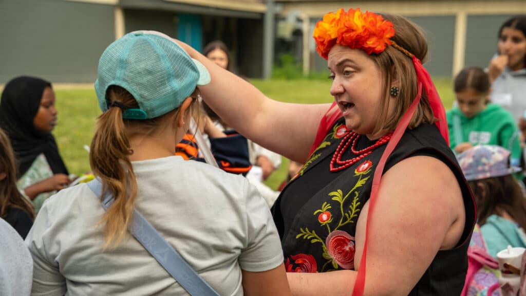 A facilitator from the Ukrainian Cultural Heritage Village teaches a young girl how to make her own flower wreath.