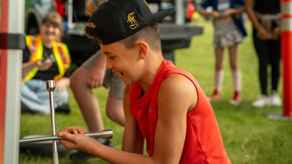 A young boy smiles as he spins a tire iron, all in pursuit of the fastest tire change time.